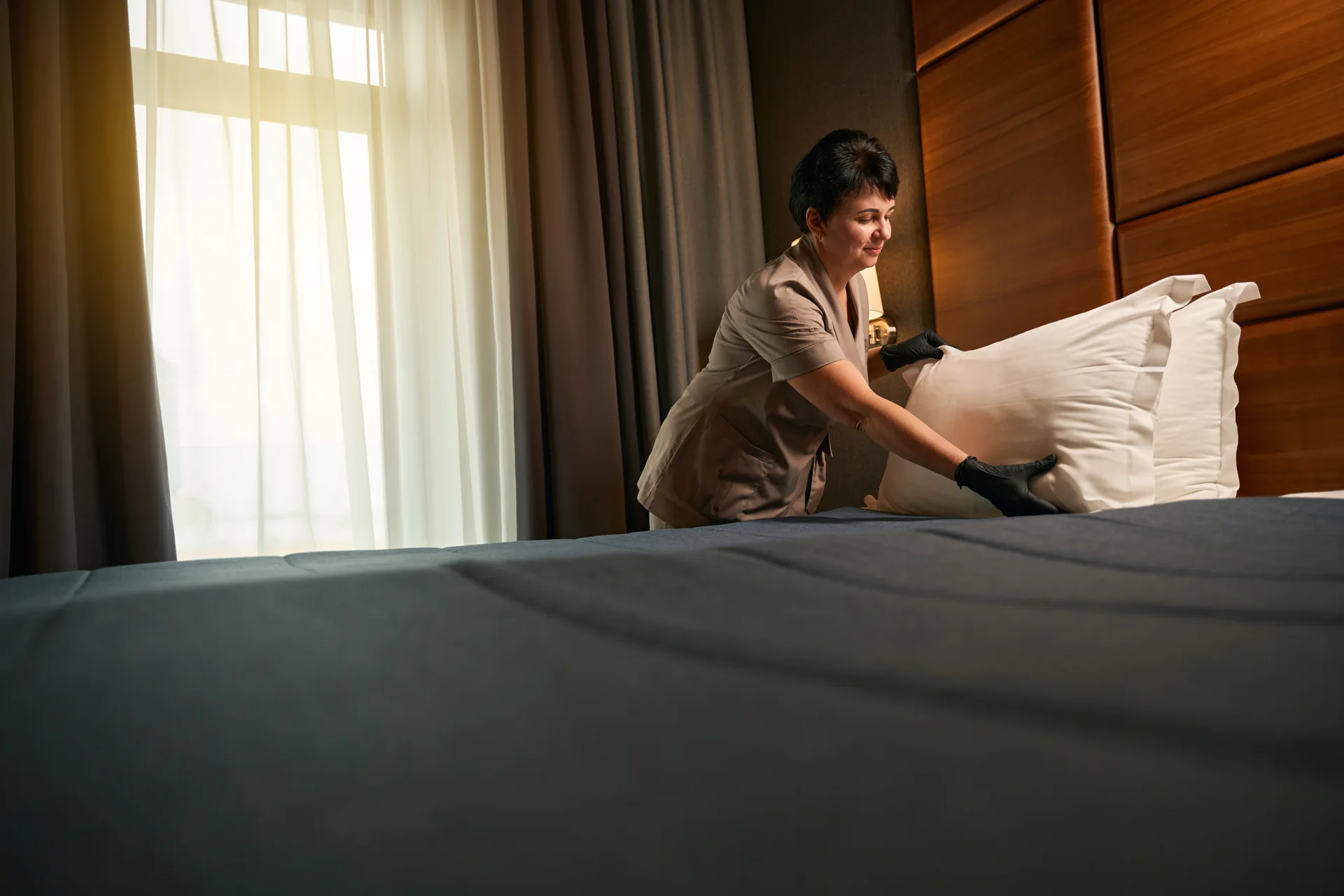 A room attendant arranging pillows on a bed
